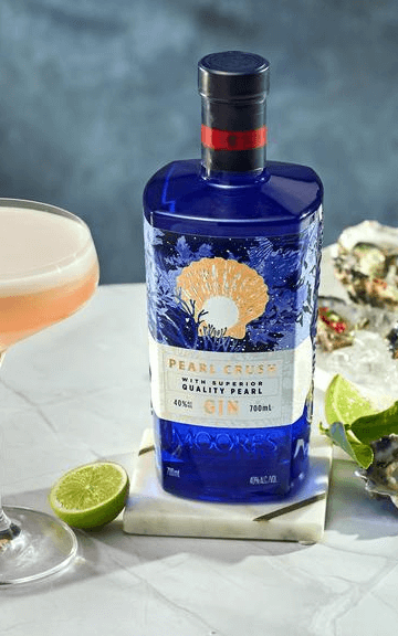 Bottle of blue gin with a lime and peach cocktail