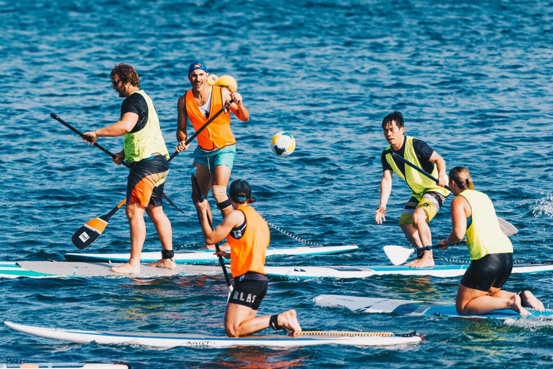 Group of people playing ball Games on SUP baords