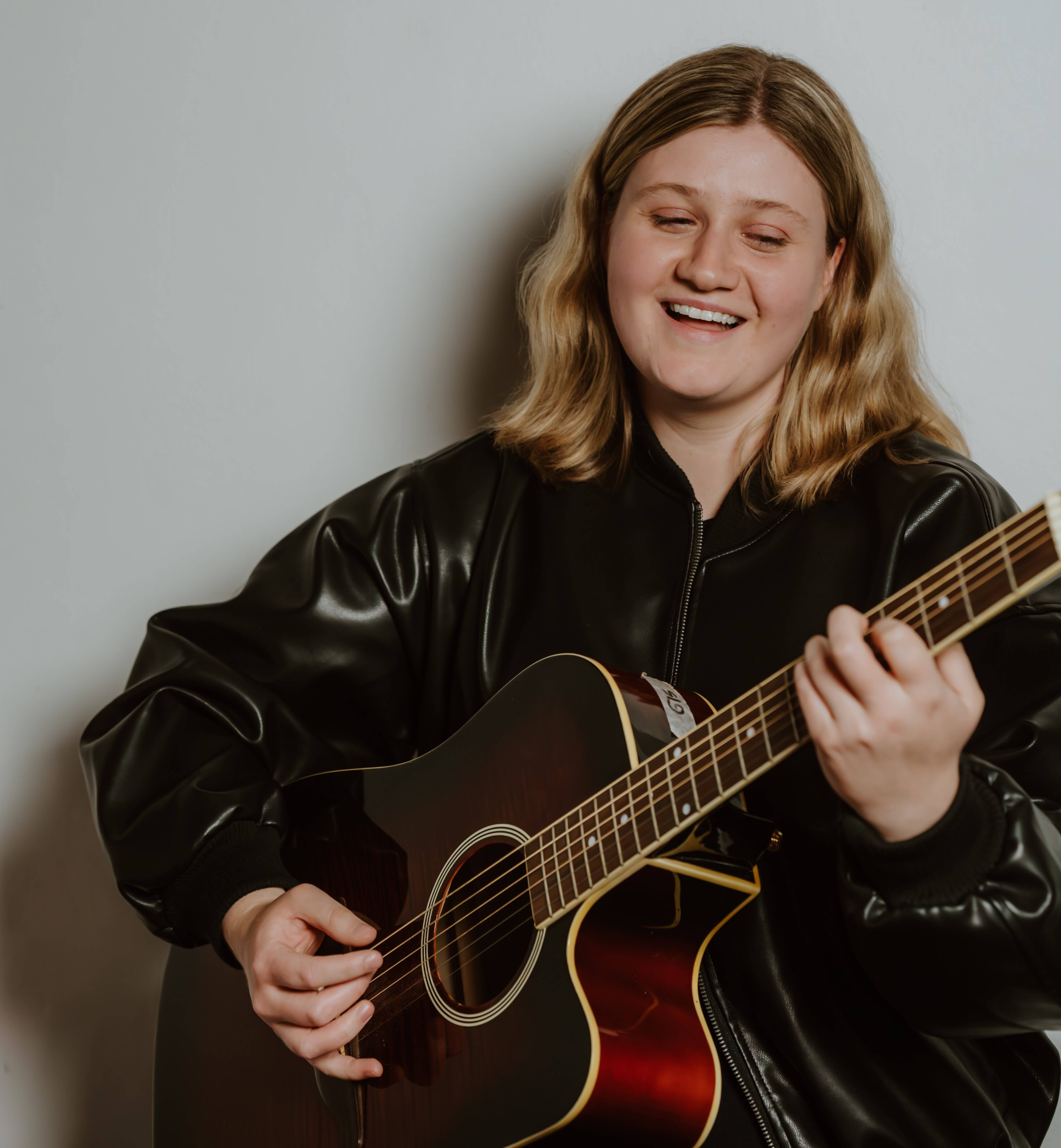 Alana Suzanne headshot musician holding guitar