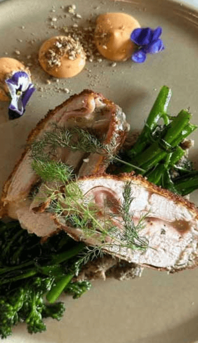 white meat on a bed of greens decorated with purple flowers