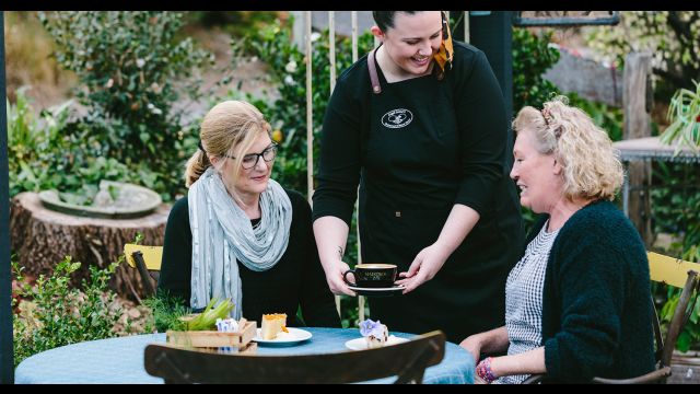 two women having coffee and cake outdoors in terraced area