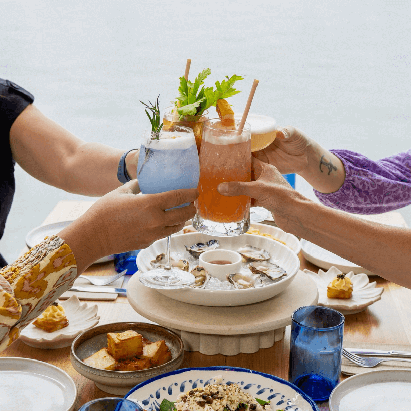 People celebrating with drinks and seafood near the water