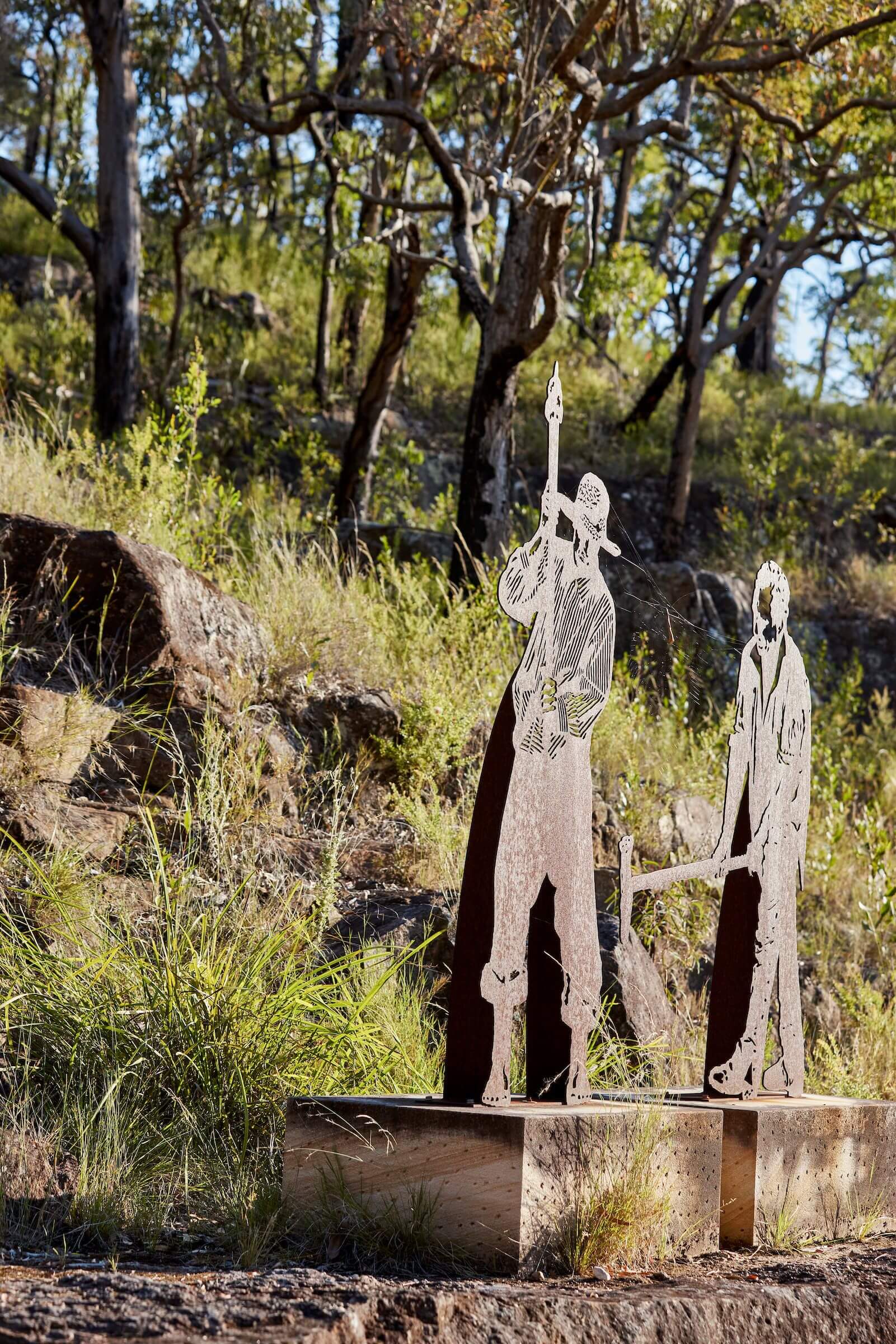 two metal sculptures of old convict workers