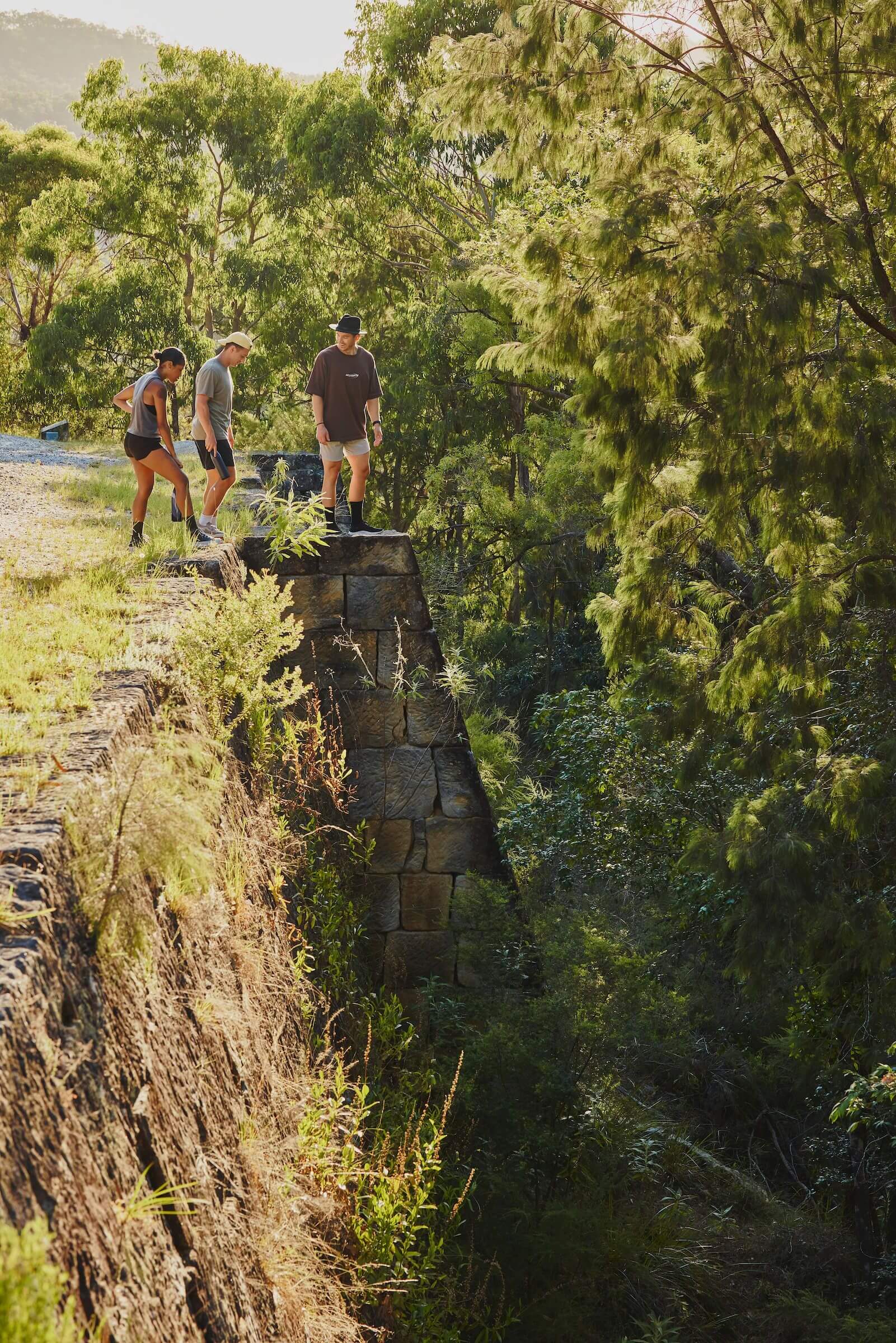 three people peer over old culvert edge