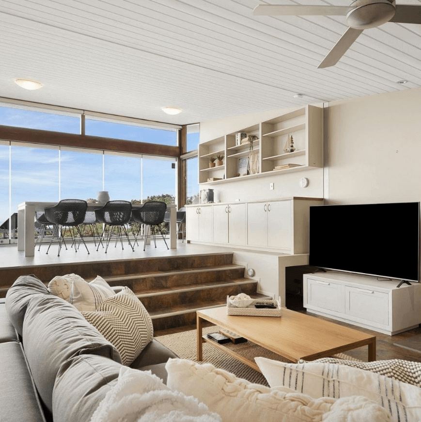 Cozy beachside lounge room with sliding doors opening up onto deck