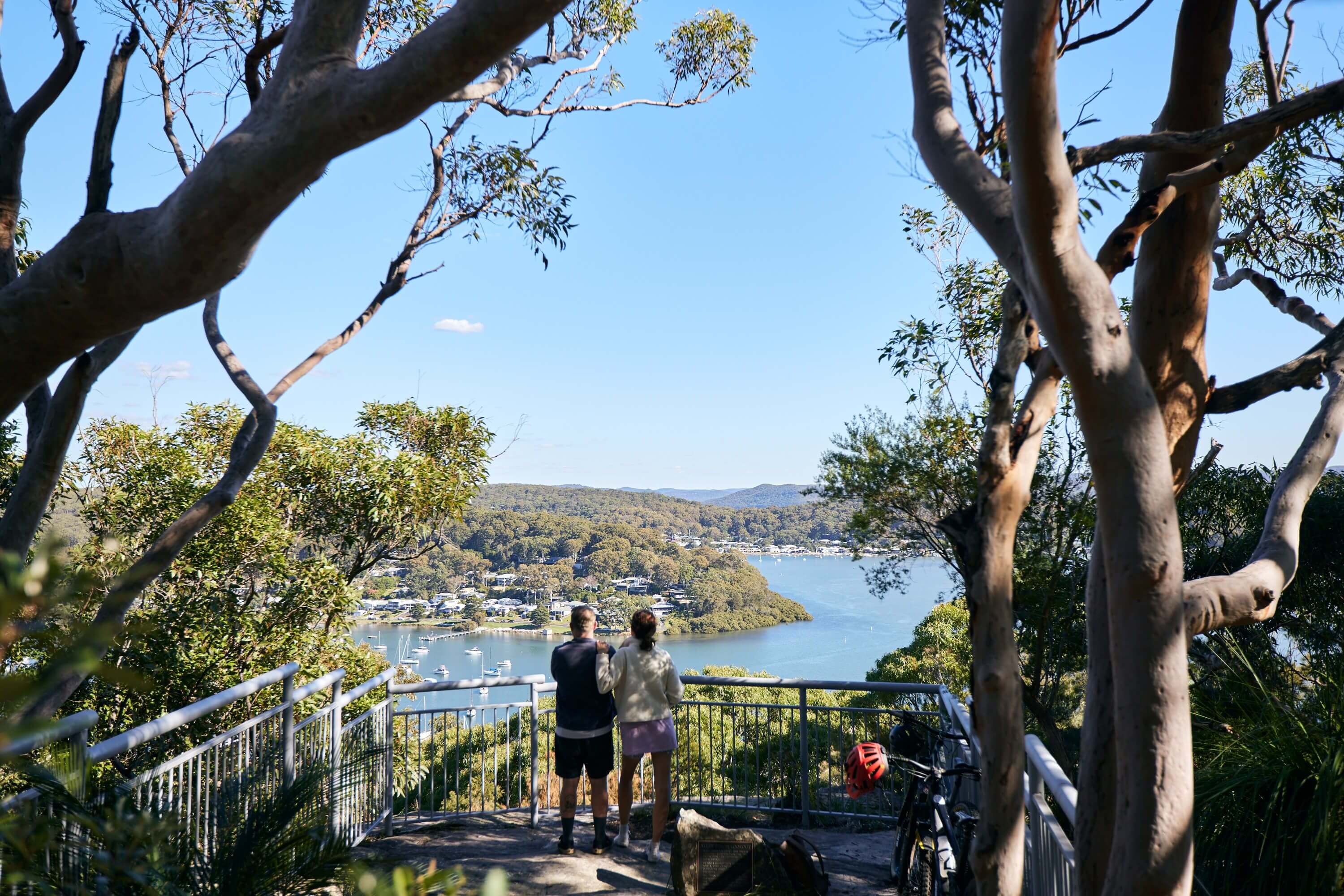 two mountain bikers stand looking at lookout view