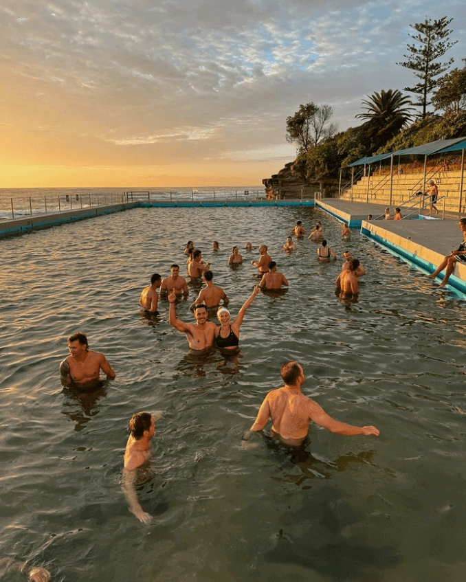Swimmers in ocean pool at sunrise