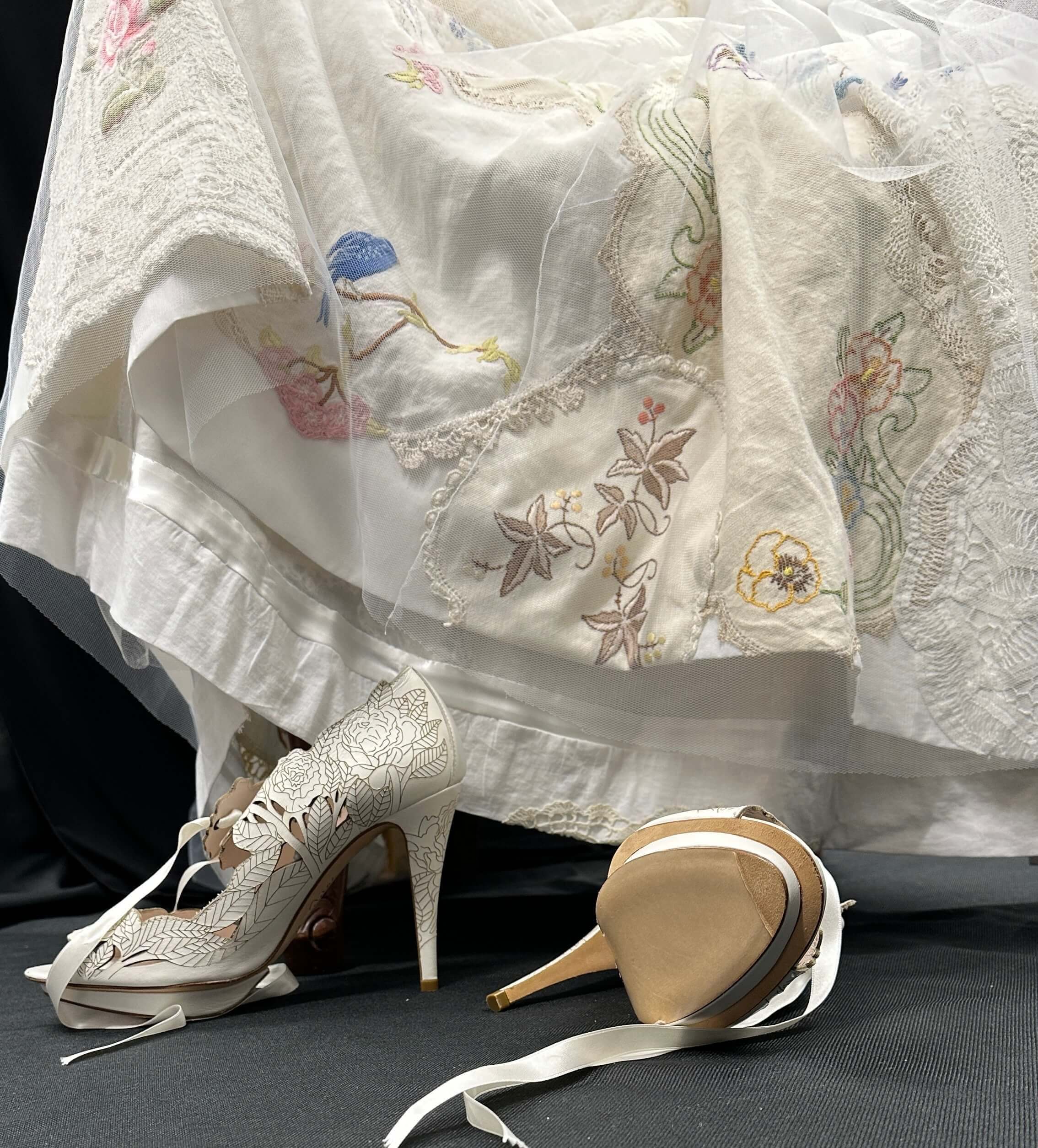 Handmade silk embrodiered wedding dress with two heel shoes in foreground