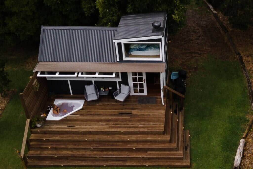 Tiny house on green grass with sprawling wooden deck