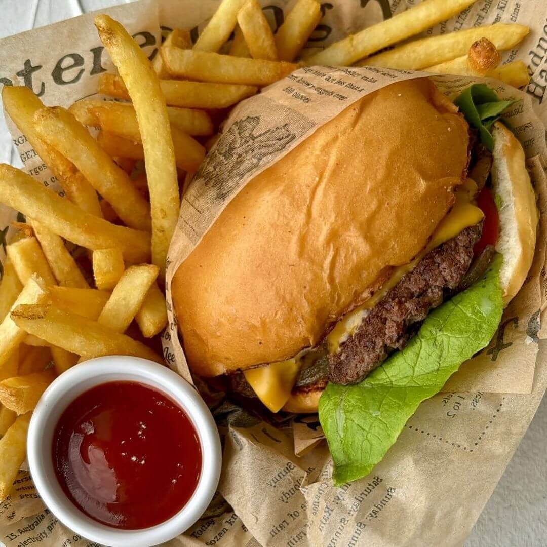 Burger with a side of hot chips and small container of tomato sauce