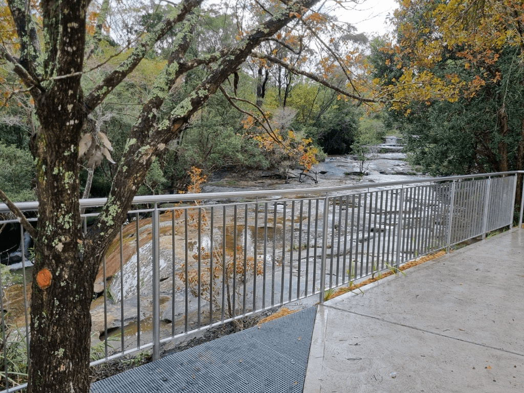 Somersby Falls lookout point with accessible pathway and falling autumnal leaves