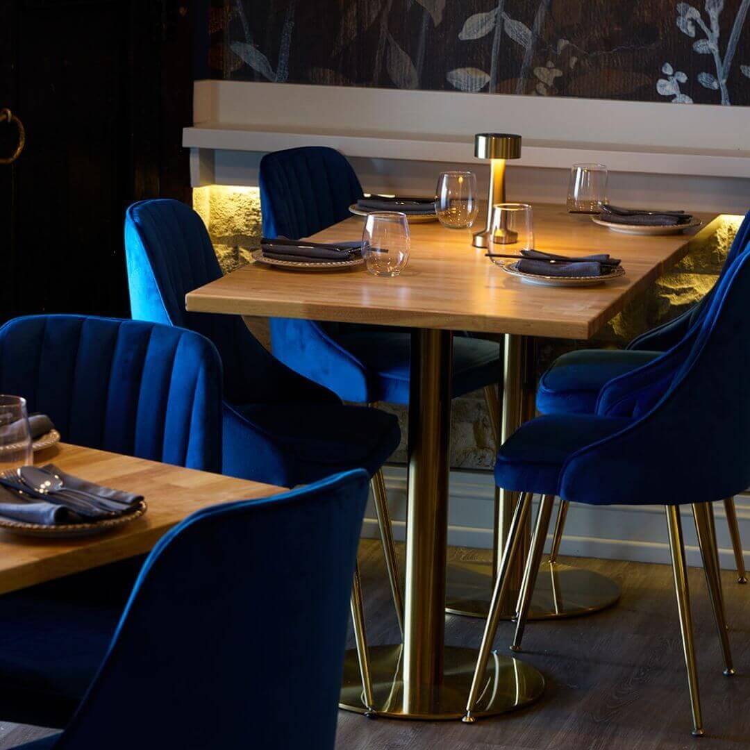 A stylish table with a gold finish surrounded by vibrant blue chairs, creating a chic dining atmosphere.