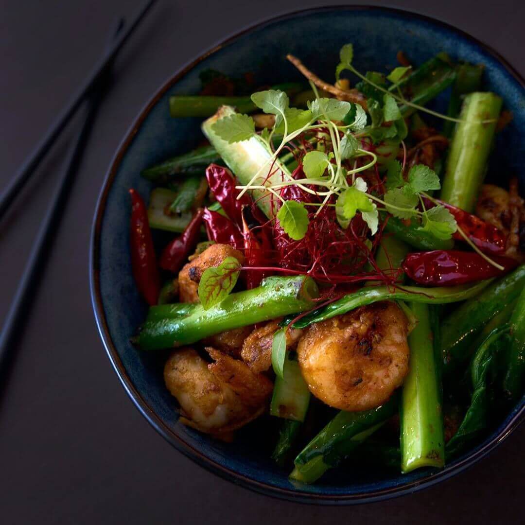 A vibrant bowl of food sits invitingly, accompanied by a pair of chopsticks and a spoon, ready to be enjoyed.