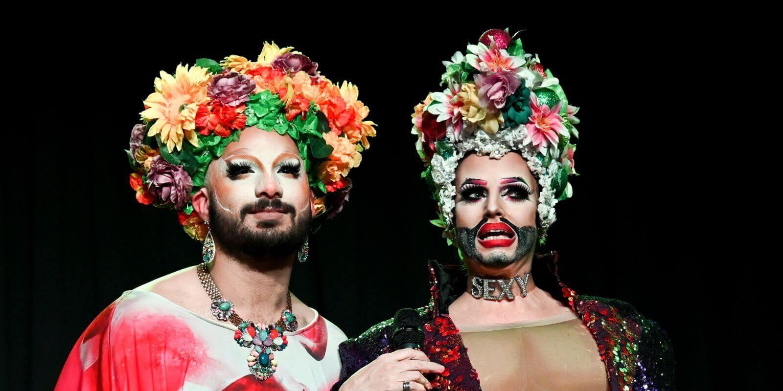 Headshot of two drag queens wearing vibrant floral headpieces 