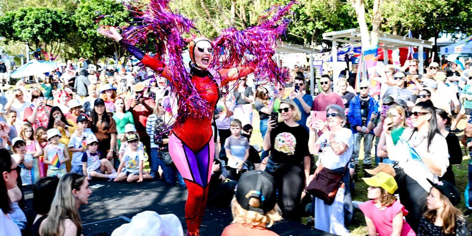 A drag queen on stage dancing whilst a crowd watches