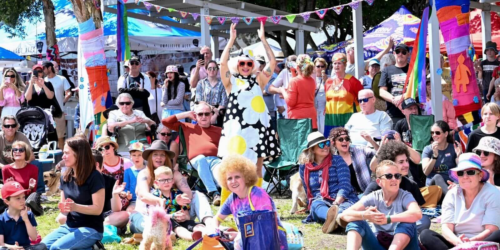 Crowd of people with market stall tents in the background