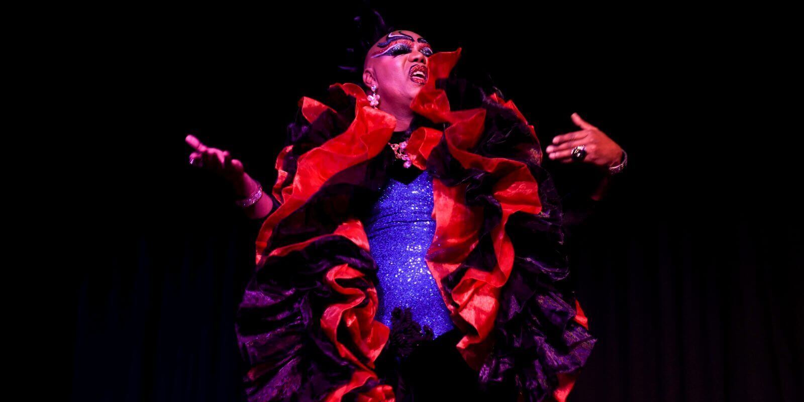 A drag queen singing wearing a flamenco style outfit