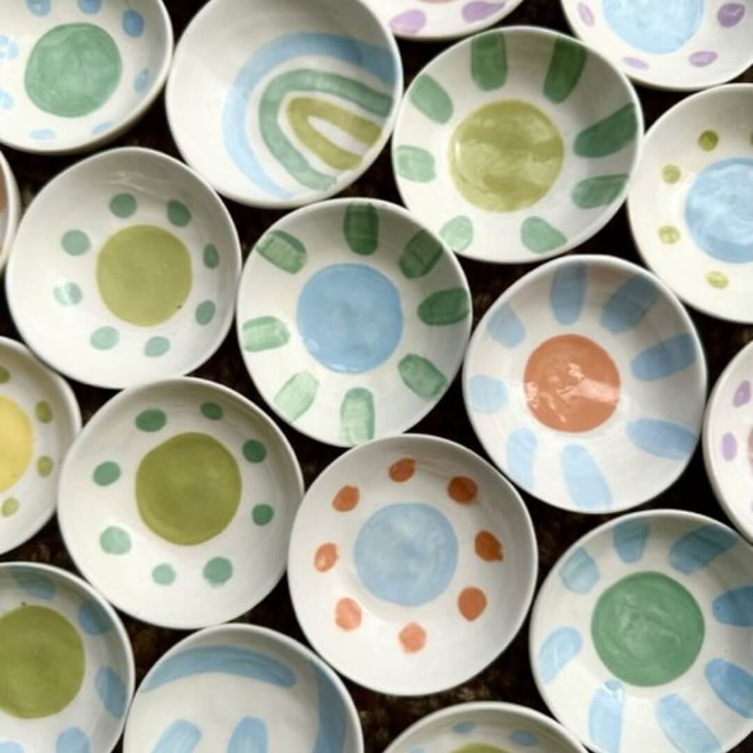 An array of mini ceramic bowls painted with circles of varying green and blue shades.