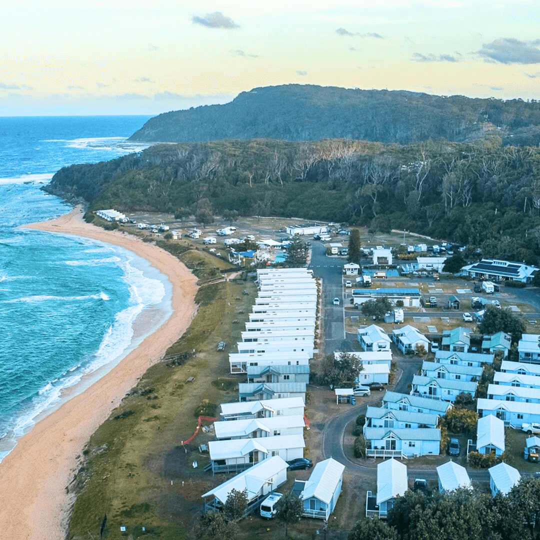 Aerial view of a coastal town featuring a beach and waterside holiday cabins