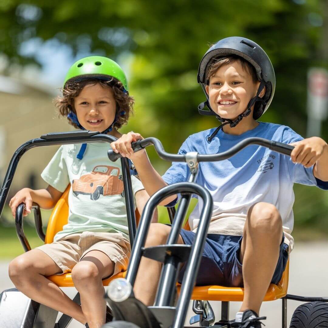 Two younger boys riding a dual pedal kart.