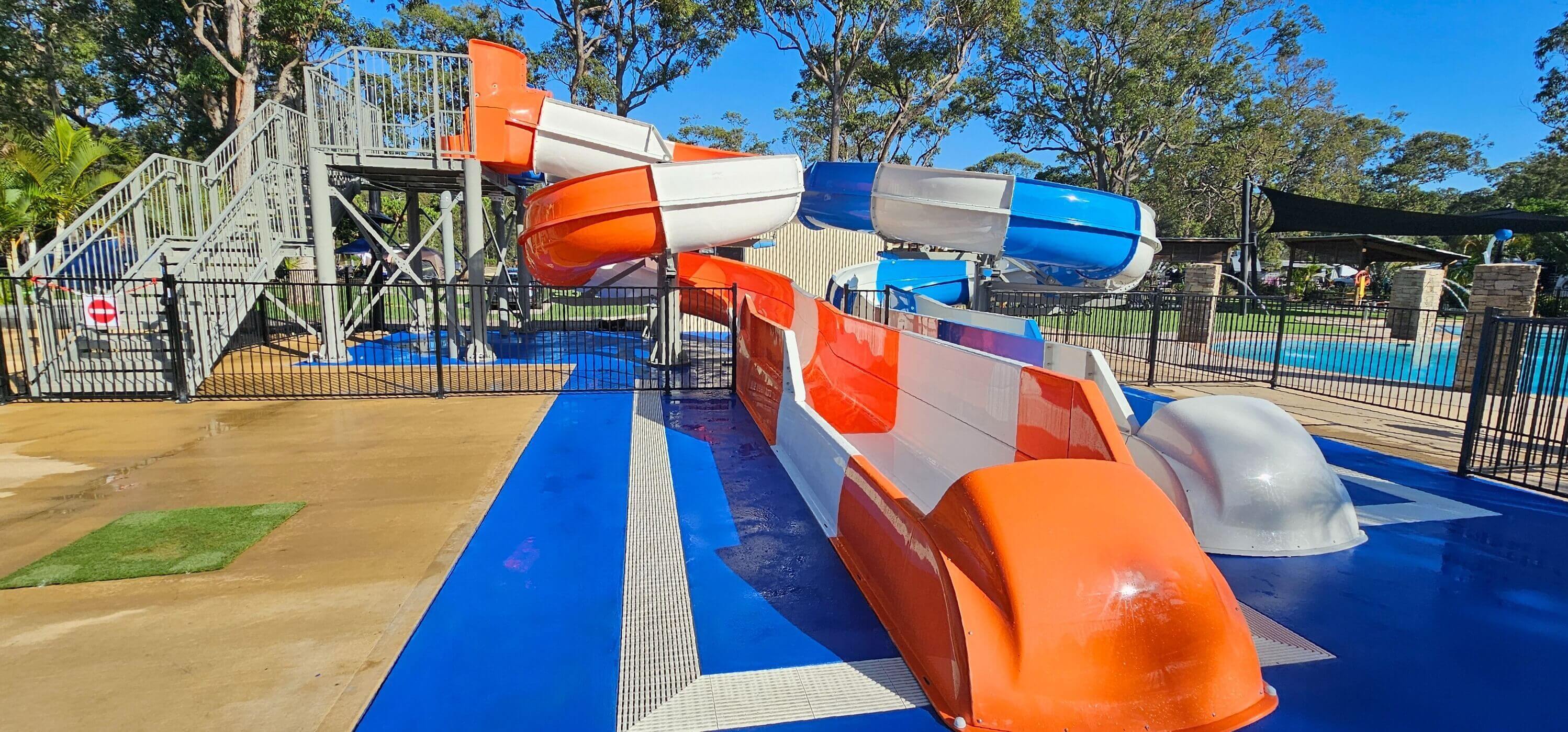 Twin water slides with one orange slide and one blue slide, side by side at a water park