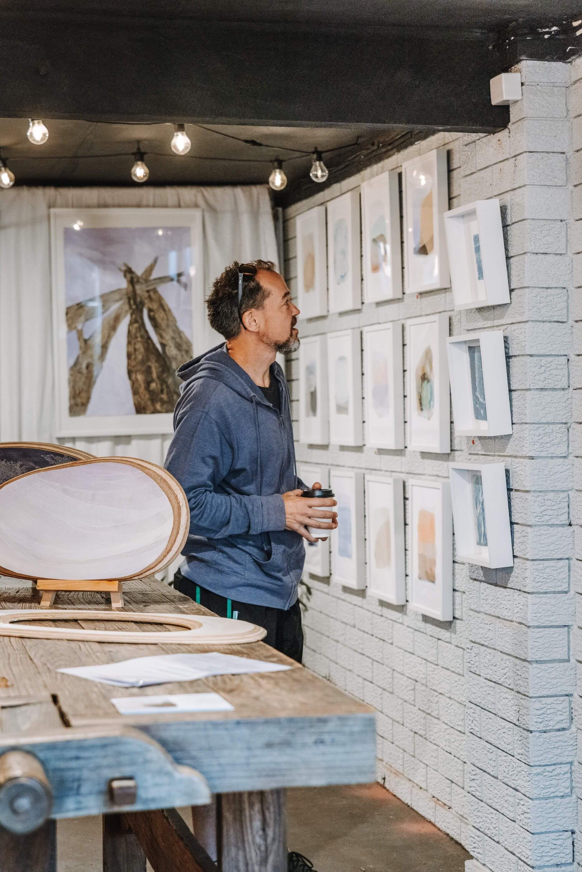 man viewing local artwork on wall with coffee