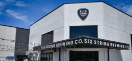 A concrete building with signage saying Six String Brewing Co