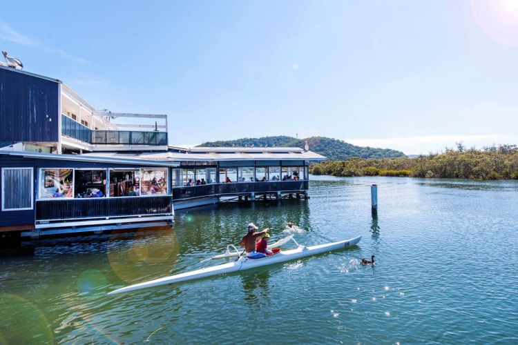 Waterfront restaurant with a couple kayaking past