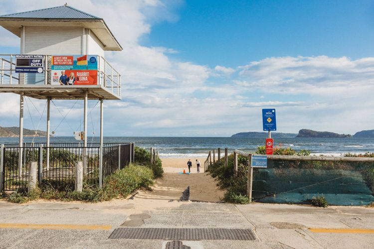 Lifeguard watch tower on the left with a sandy path leading to a beach