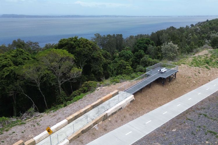 A raised platform that sits next to a walkway. The platform offers abundant views of bushland and ocean.