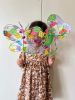 Girl holding up 2 butterfly sun catcher wands