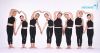 8 girls wearing matching dance costumes, smiling and making love heart shapes with their arms.