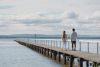 A man and woman walking along a long jetty that juts out into the middle of a lake